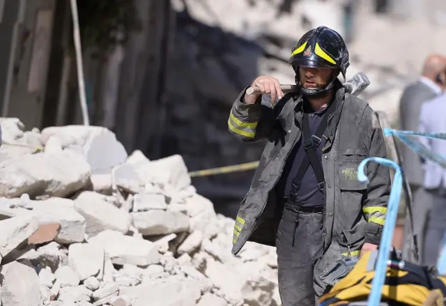 A firefighter walks past rubble in Amatrice