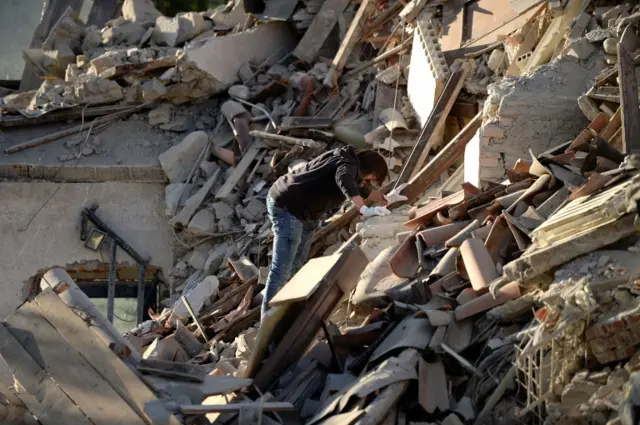 A man searches damaged buildings in Amatrice