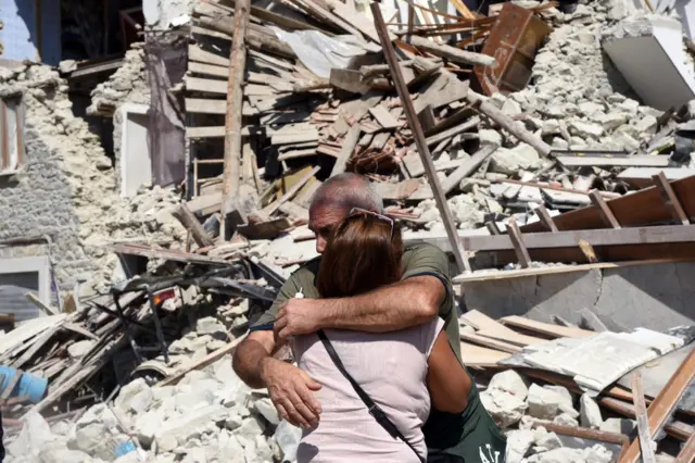 Two residents hug each other next to collapsed and damaged houses in Pescara del Tronto, central Italy, 24 August 2016