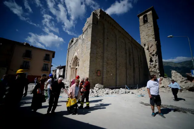 People walk past an earthquake-damaged church in Amatrice on 24 August 2016