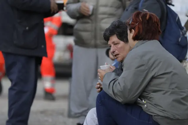 People drink in a tent camp near Pescara Del Tronto, Italy (25 August 2016)