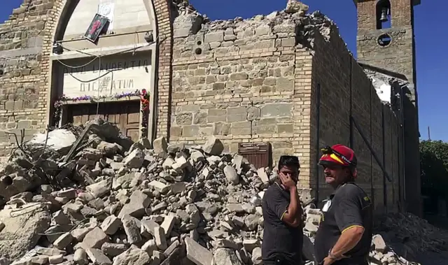 rescuers standing by a damaged church