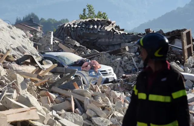 Rescue workers search the rubble of collapsed buildings in Pescara del Tronto (25 August 2016)