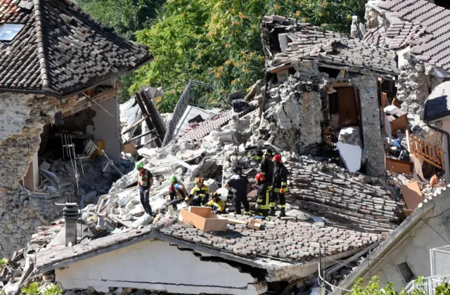 Rescue workers search the rubble of collapsed buildings in Pescara del Tronto (25 August 2016)