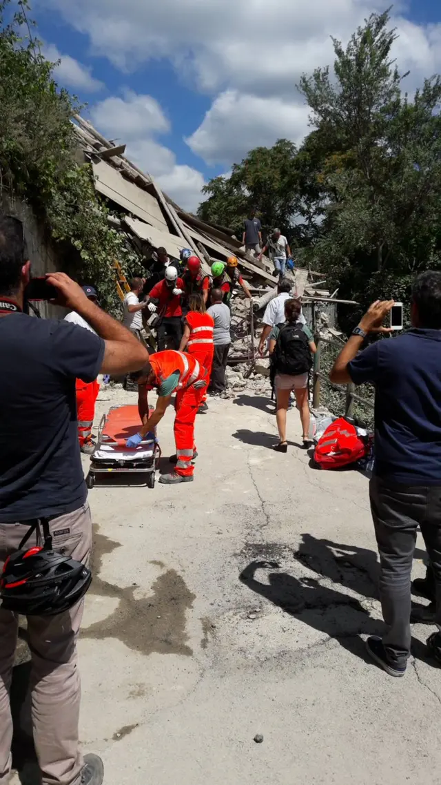 rescuers getting a stretcher ready while photographers look on