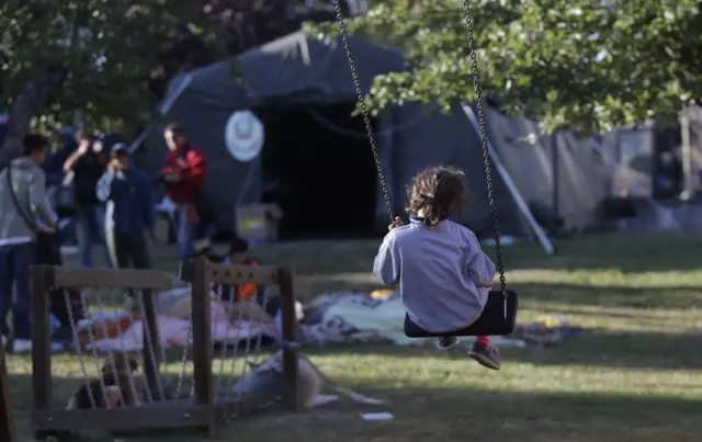 A child sits on a swing in a park where the Italian Civil Protection has set up a camp for the survivors of Wednesday's earthquake in Amatrice, central Italy (25 August 2016)