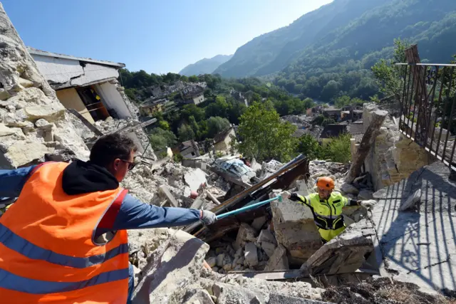 Rescue workers search the rubble of collapsed buildings in Pescara del Tronto (25 August 2016)