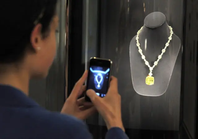 A visitor takes a photograph of the 'Tiffany Diamond' on display at the Tiffany and Co jewellery store on on the Champs Elysees