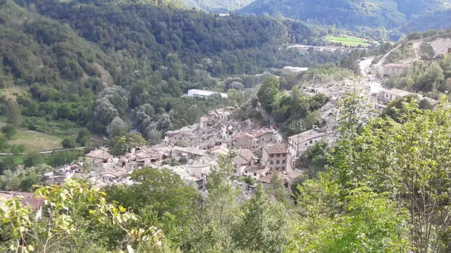 the village of Pescara del Tronto seen from afar, with some buildings still intact but many destroyed