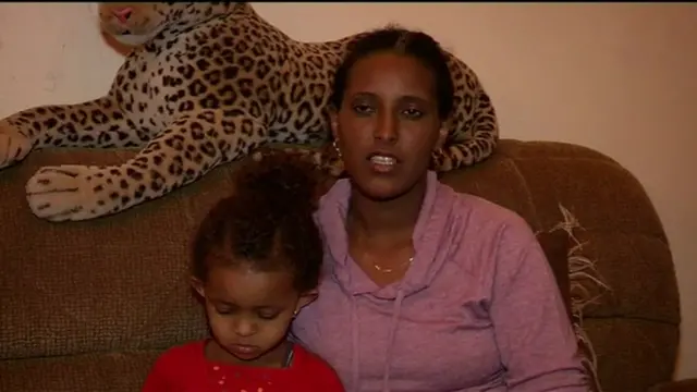 Feyisa Lelisa's wife and daughter sit on a sofa at their home