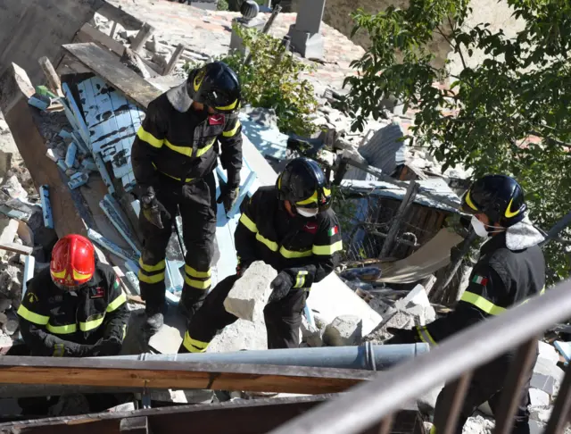 Rescue workers search the rubble of collapsed buildings in Pescara del Tronto (25 August 2016)