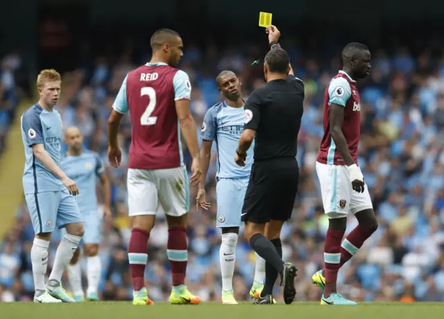 Man City's Fernandinho receives a yellow card