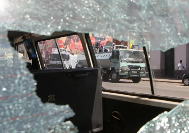 Anti-riot police are seen trough a broken car window after they clashed with protesters during a march against President Robert Mugabe"s government"s handling of the economy in Harare, Zimbabwe, August 3, 2016