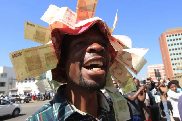 A man wears a hat with old Zimbabwean dollar notes during demonstrations in Harare, Wednesday, Aug. 3, 2016