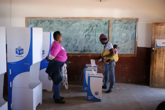 A women with a child on her back casts a vote during tense local munincipal elections in Vuwani, South Africa"s northern Limpopo province, August 3, 2016.