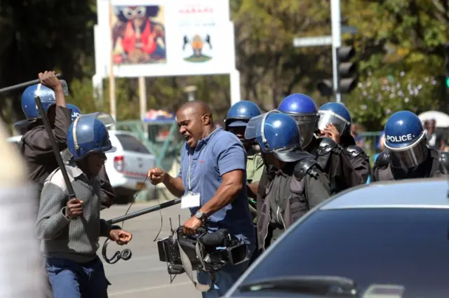 A cameraman is hit by the police during demonstrations in Harare, Wednesday, Aug. 3, 2016.