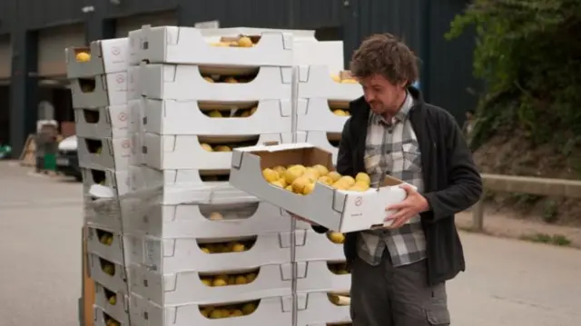 A man holds a box of lemons