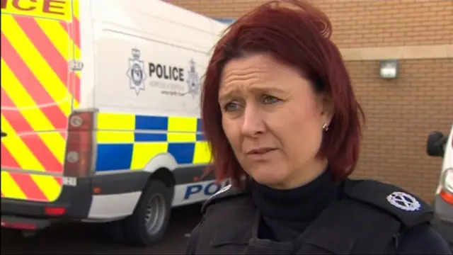 Assistant chief constable Sarah Hamlin, standing to one side of a police van