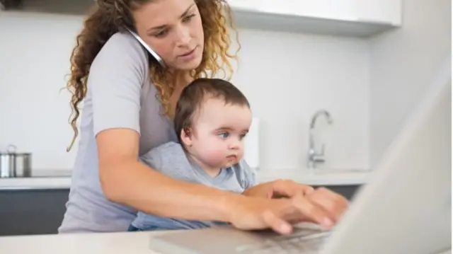 Mother on computer holding baby