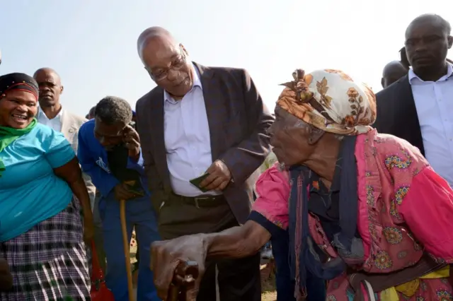 A handout photograph made available by the South African Government Communication and Information System (GCIS) shows President Jacob Zuma (C) talks to an elderly voter as he waits to cast his vote at Ntolwane Primary School, during the municipal elections in Nkandla,