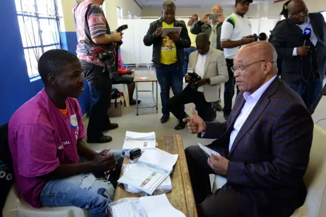 A handout photograph made available by the South African Government Communication and Information System (GCIS) shows President Jacob Zuma (R) talks with an electoral official before casting his vote at Ntolwane Primary School, during the municipal elections in Nkandla, KwaZulu Natal, South Africa, 03 August 2016.