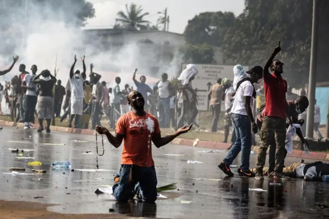 Man kneels on the road with hand outstretched amid protests