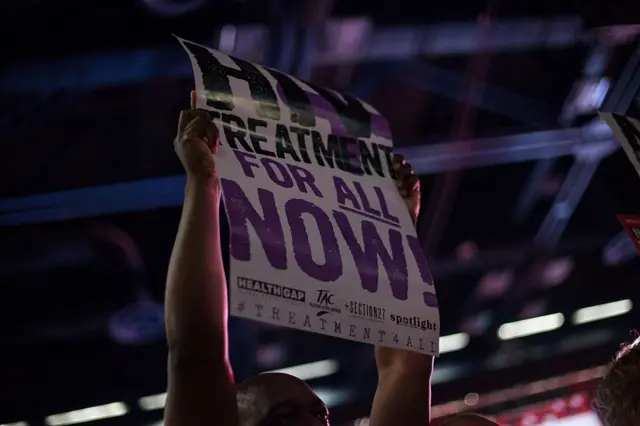 Campaigner holding placard calling for treatment for all