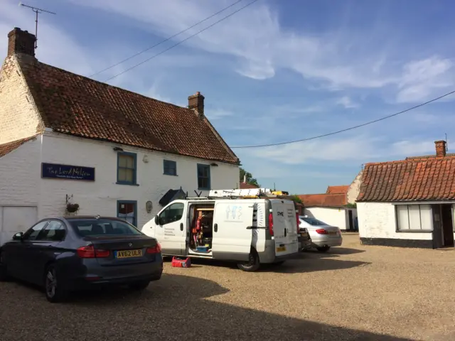 Exterior of pub, with van and cars in the parking area