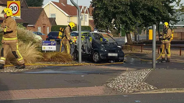 Fire crews by the burnt-out car