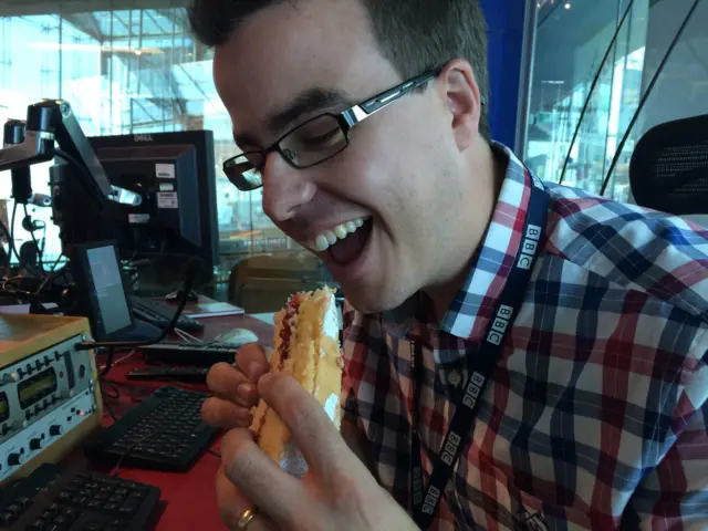 Producer Edd Smith holding a slice of cake and smiling