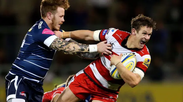 Billy Burns of Gloucester Rugby is caught by Sam James of Sale Sharks