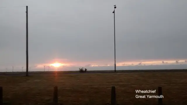 Sun rise over Great Yarmouth area, showing open land, with wind turbines in the distance