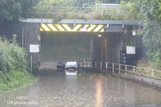 Car trapped in flood water under rail bridge