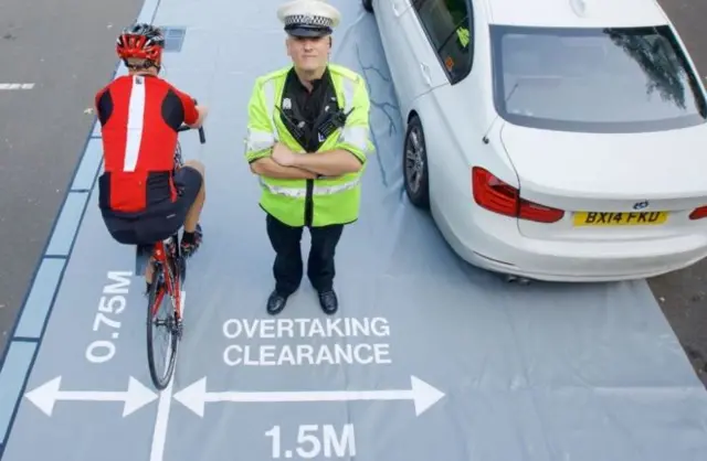 Officer showing "safe overtaking clearance distance"