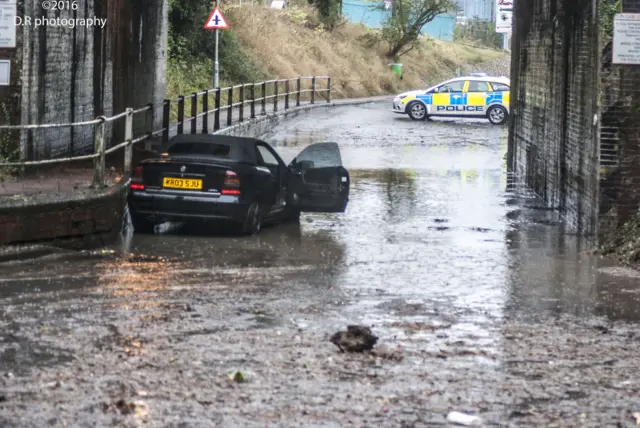 Flood water has receded, showing a car with open door, and a police vehicle