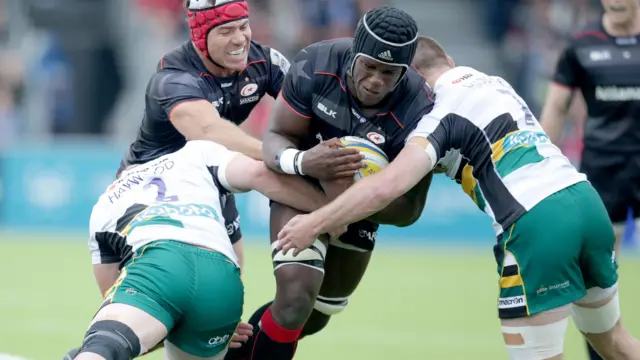 Maro Itoje of Saracens is stopped by Mikey Haywood and Teimana Harrison of Northampton