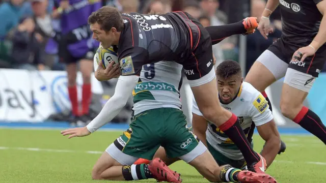 Saracens' Alex Goode is lifted in a tackle by Northampton's Lee Dickson