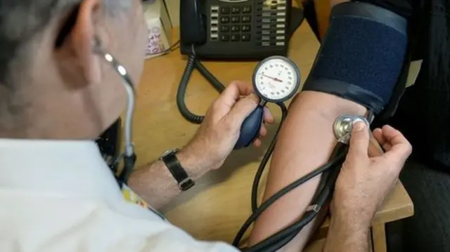 GP with patient blood pressure check