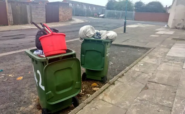 Wheelie bins overflowing with plastic buckets and rubbish