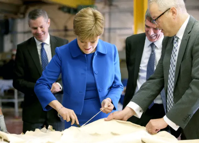 First Minister Nicola Sturgeon is shown how leather hides are trimmed with managing director Colin Wade [right] looking on