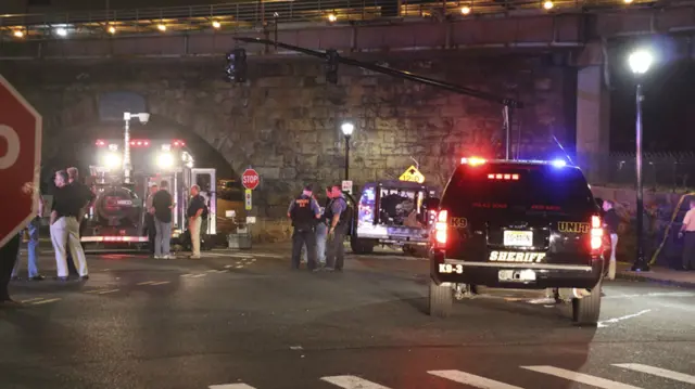 Bomb squad personnel stand around the scene of an explosion near the train station, early Monday, Sept 19, 2016, in Elizabeth, N.J.