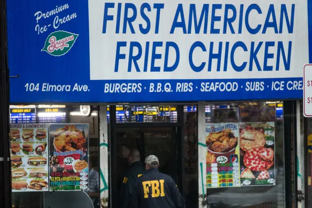 Members of the Federal Bureau of Investigation (FBI) and other law enforcement officials enter a fried chicken store that is underneath the residence being investigated in connection to Saturday night"s bombing in Manhattan