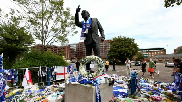 Sir Bobby Robson statue with tributes