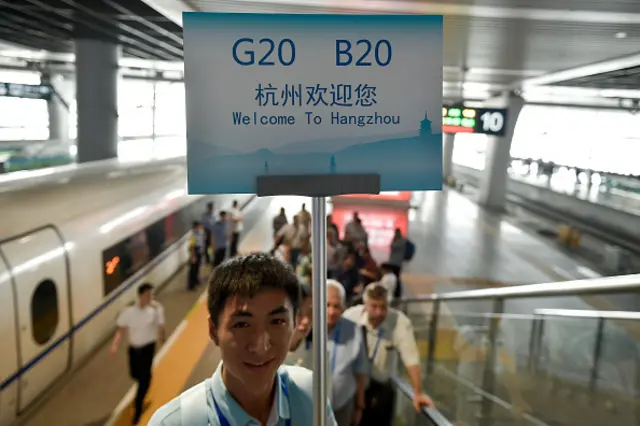 A volunteer leads G20 attendees at Hangzhou railway station