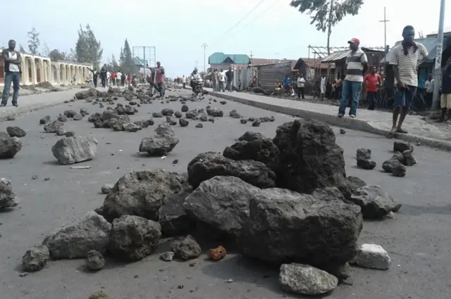 road bloacked with rocks as protesters stand in background