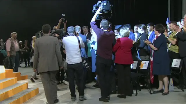 Tim Farron surrounded by cameras as he leaves the stage