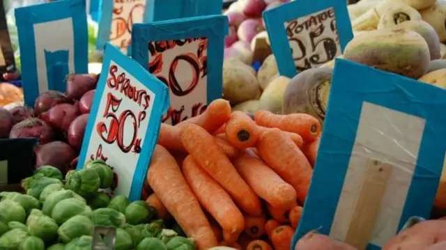 Greengrocer displaying vegetables for sale in both pounds and kilograms