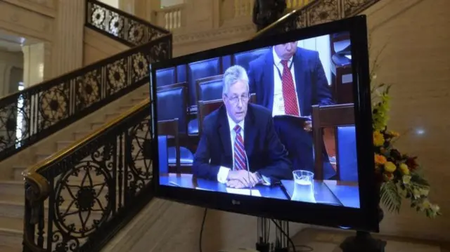 A Tv in the Great Hall at Stormont shows Peter Robinson appearing before the Finance Committee