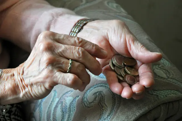 An elderly woman holding coins