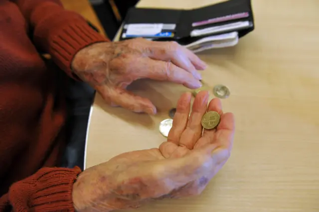 An elderly woman holding a coin